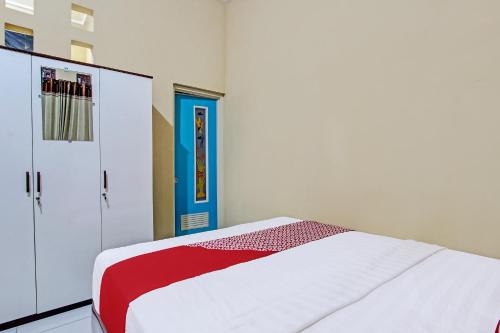 a bedroom with a white bed and a blue door at Hotel O Amole Paviliun Syariah in Cilacap