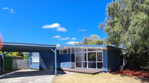 a blue house with a porch and a tree at Beach Cottage. 100m to the beach 9minutes to Hot Springs. Pet Friendly in Capel Sound