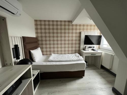 Schlafzimmer mit einem Bett und einem Schreibtisch mit einem TV in der Unterkunft Hotel Innception in Köln