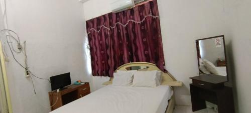 Schlafzimmer mit einem Bett mit einem Spiegel und einem roten Vorhang in der Unterkunft SPOT ON 92338 Karin Kost in Banjarbaru