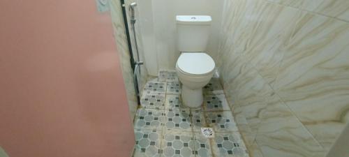 baño con aseo y suelo de baldosa. en SPOT ON 92338 Karin Kost, en Banjarbaru