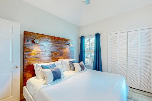 sypialnia z białym łóżkiem z drewnianym zagłówkiem w obiekcie Whitecap Retreat w mieście Wyspa Padre