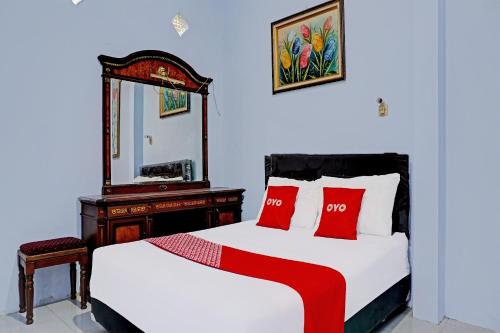 1 dormitorio con cama con almohadas rojas y espejo en OYO 92359 Kost Maluku 36 Family Residence, en Blitar
