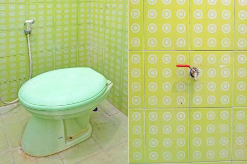 y baño con aseo en una pared de azulejos. en OYO 92359 Kost Maluku 36 Family Residence, en Blitar