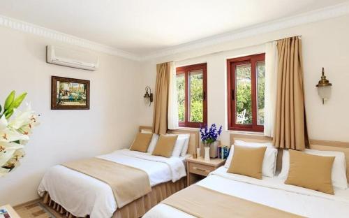 SogutにあるVilla Askimの白い壁と窓が備わる客室で、ベッド2台が備わります。