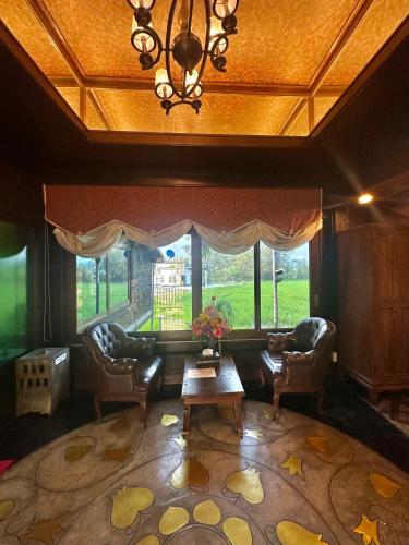 a living room with chairs and a table and a large window at Bantunglom Resort in Mae Rim