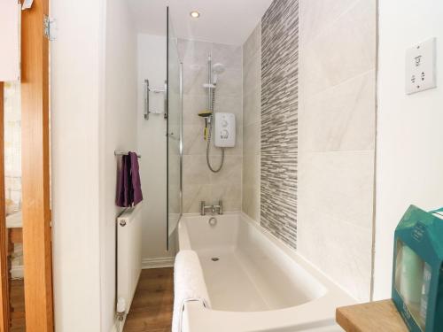 a white bathroom with a tub and a shower at Beach Cottage in Kinghorn