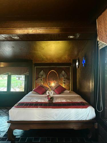 a bedroom with a large bed with red pillows at Bantunglom Resort in Mae Rim