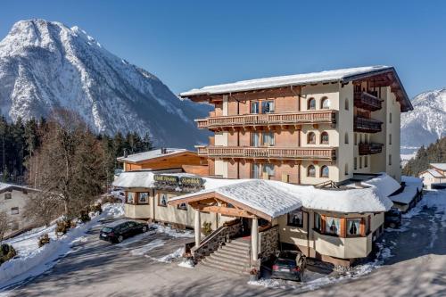 a large building with a snow covered mountain in the background at Naturhotel Alpenblick in Maurach