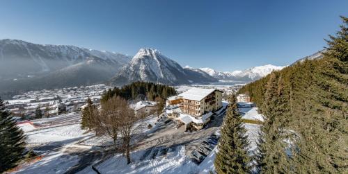 a building on a snowy hill with a mountain in the background at Naturhotel Alpenblick in Maurach