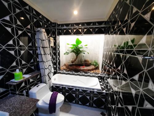 a bathroom with a black and white tiled wall at Fancy Carp Resort in Cha Am