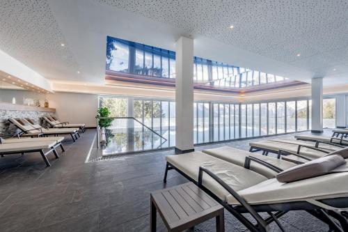 a waiting room with tables and chairs and large windows at Naturhotel Alpenblick in Maurach