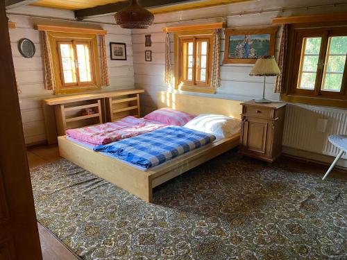 1 dormitorio con 1 cama, escritorio y ventanas en Roubenka u potoka Jizerské hory, en Desná