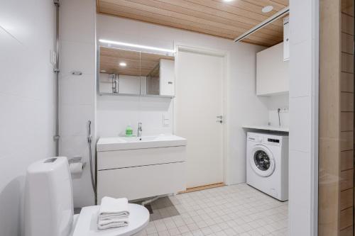 a bathroom with a toilet and a sink and a washing machine at 2ndhomes Tampere Brand New "Station" Apartment with Sauna in Tampere