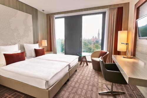 ein Hotelzimmer mit einem Bett und einem großen Fenster in der Unterkunft Steigenberger Hotel Bremen in Bremen