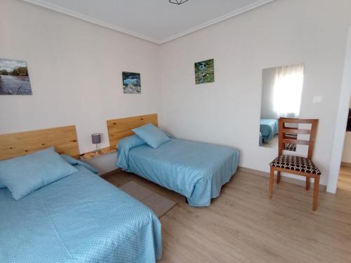 a bedroom with two beds and a chair in it at La Casa del Limonero in Suances