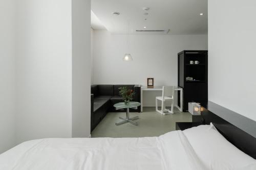 a white bedroom with a bed and a couch at Mangrove Dongdaemun in Seoul