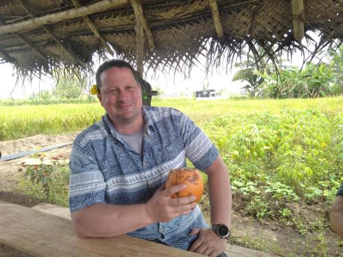 a man holding an orange in front of a field at Dambulla Tree House in Dambulla