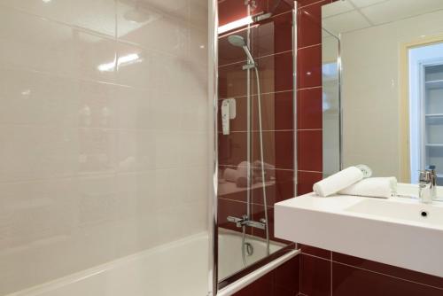 La salle de bains est pourvue d'une douche, d'un lavabo et d'un miroir. dans l'établissement Hôtel Limouzi Tulle Centre, à Tulle