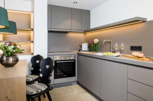 a kitchen with gray cabinets and a counter with chairs at Fügenschuh's Ferienwohnungen in Bad Hindelang