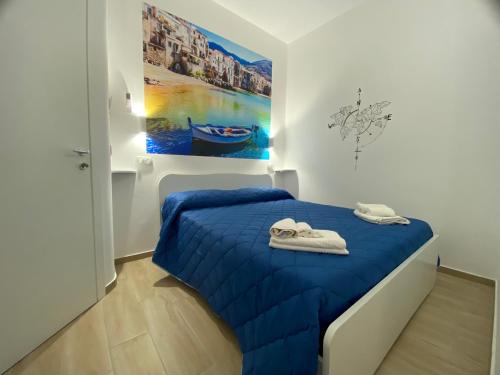 a bedroom with a blue bed with a painting on the wall at IN CENTRO ROOMS Vicino Cefalù SELF-CHEK-IN in Campofelice di Roccella