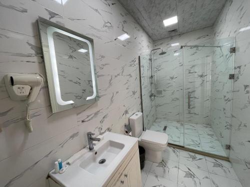 a white bathroom with a sink and a shower at NOBEL Hotel in Baku