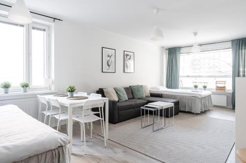 a white living room with a couch and a table at Spacious Downtown Apartment with Balcony next to Restaurants - Hosted by 2ndhomes in Tampere