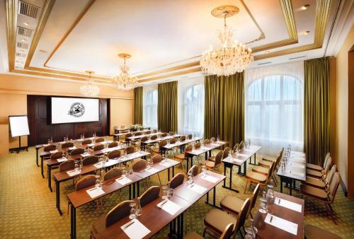 a large room with tables and chairs and a chandelier at Grand Hotel Praha in Tatranská Lomnica
