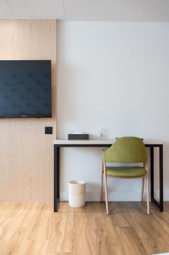 a desk with a chair and a television on a wall at Hub Hotel Zhongli in Zhongli