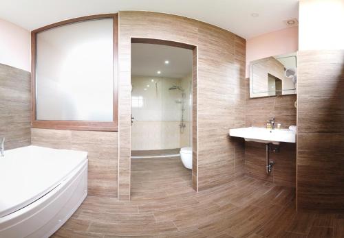 ein Badezimmer mit einer Badewanne, einem Waschbecken und einem Spiegel in der Unterkunft Clepsydra Residence in Plowdiw