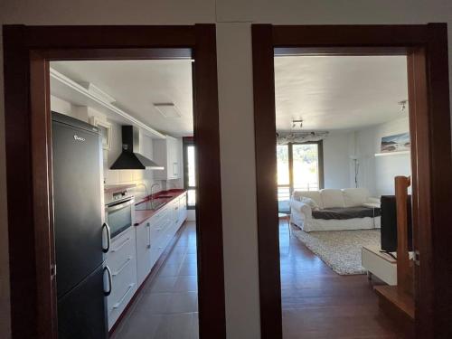 a kitchen with white cabinets and a living room at Duplex Bahía de Santoña in Santoña