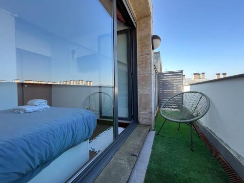 1 dormitorio con 1 cama y 1 silla en el balcón en Duplex Bahía de Santoña en Santoña