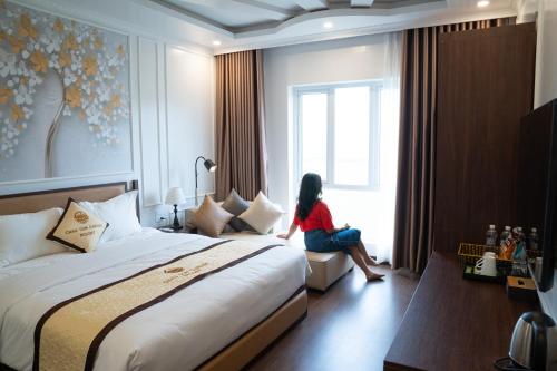 une femme assise près d'une fenêtre dans une chambre d'hôtel dans l'établissement Chau Son Garden Hotel & Resort Ninh Binh, à Ninh Binh