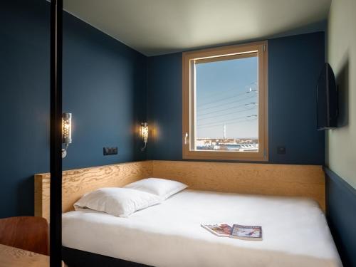 a bed in a blue room with a window at Eklo Lyon in Vénissieux