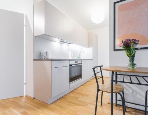a kitchen with white cabinets and a table with a vase of flowers at Modern Apartment with free garage in Vienna
