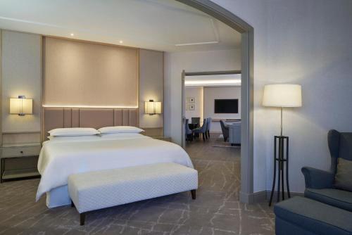 a bedroom with a large white bed and a chair at Sheraton Imperial Kuala Lumpur Hotel in Kuala Lumpur