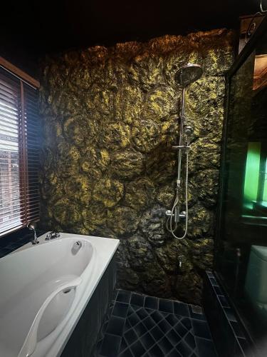 a stone bathroom with a tub and a shower at Bantunglom Resort in Mae Rim