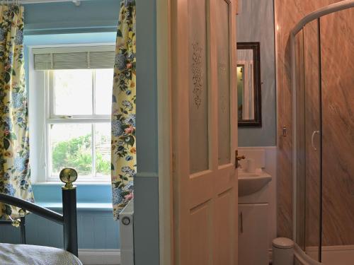 a bathroom with a door and a sink and a window at The Rockery in Shap