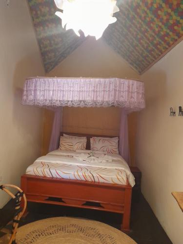 Dormitorio pequeño con cama con dosel en Green Garden Hostel en Arusha