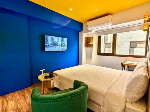 a blue bedroom with a bed and a green chair at Journey Town Inn in Taipei