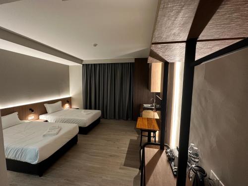 a hotel room with two beds and a window at Roxy Hotel Aiman in Kuching