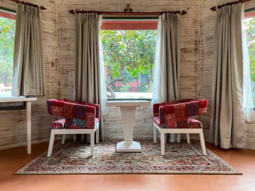 two chairs and a table in a room with a window at Habitus Resort in Mandrem