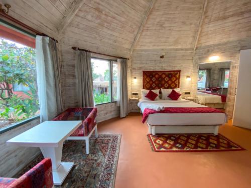 a bedroom with two beds and a table in a room at Habitus Resort in Mandrem