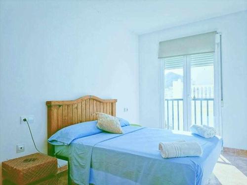 um quarto com uma cama com lençóis azuis e uma janela em LAS PITAS Piso a metros de la playa em Carboneras