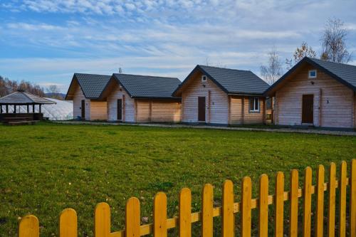a row of houses behind a wooden fence at Osada Kryspinów in Cholerzyn