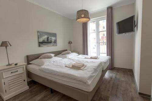 um quarto com uma cama, uma televisão e uma janela em Villa-Borwin-Apartment-1 em Kühlungsborn