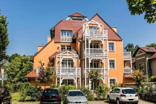 Villa-Senta-Apartment-13 في كولونغسبورن: منزل برتقالي كبير مع سيارات متوقفة أمامه