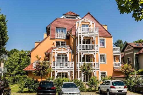 une grande maison orange avec des voitures garées devant elle dans l'établissement Villa-Senta-Apartment-15, à Kühlungsborn