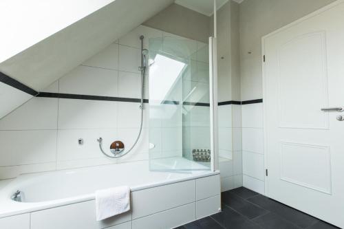 La salle de bains blanche est pourvue d'une douche et d'une baignoire. dans l'établissement Villa-Senta-Apartment-16, à Kühlungsborn