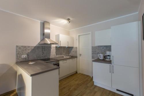 eine Küche mit weißen Schränken und einer Arbeitsplatte in der Unterkunft Sunnevelt Apartment 12 in Kühlungsborn